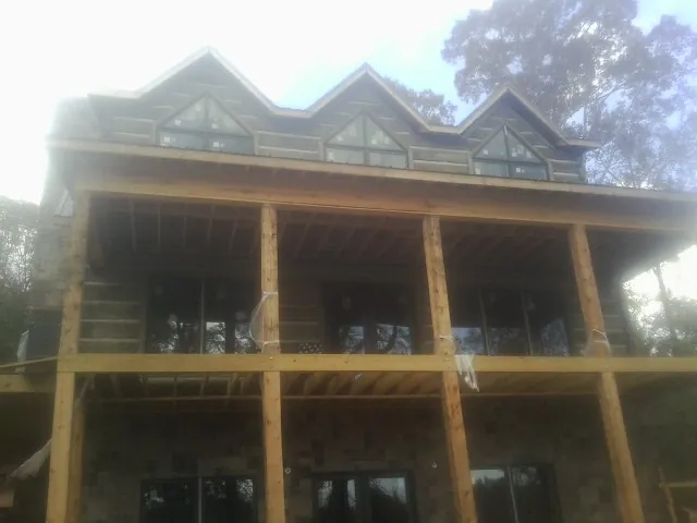 Dormers and porch framing on a large log home under construction — Roof Coating work by our crew in Cheshire