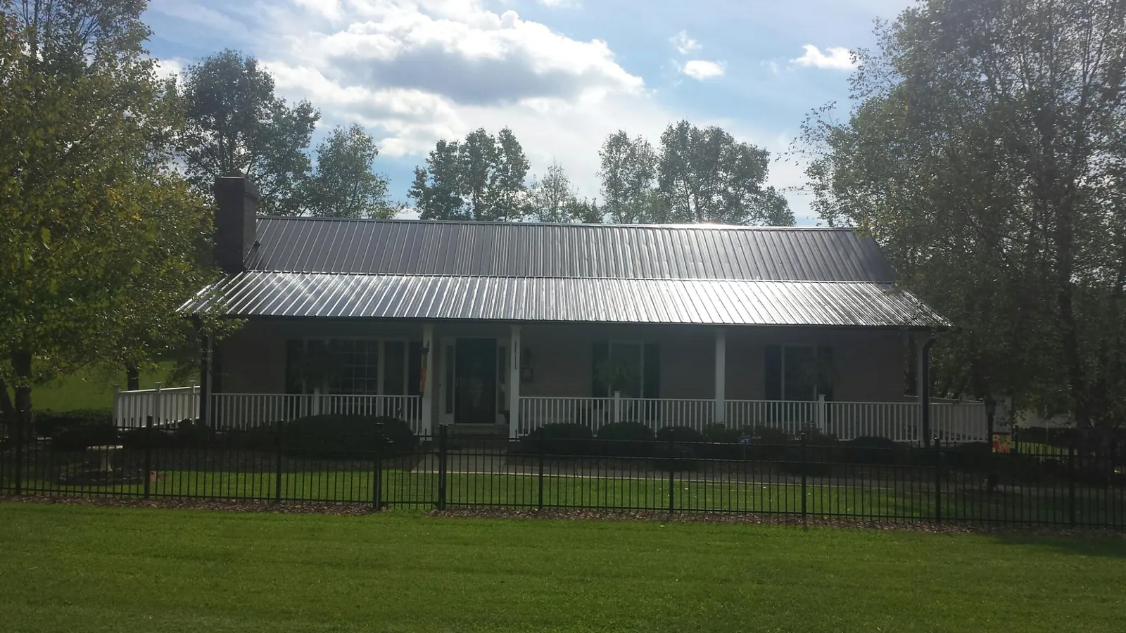 Gray metal roof on a brick ranch with a full width front porch — Gutter Guard Installation work by our crew in Cheshire