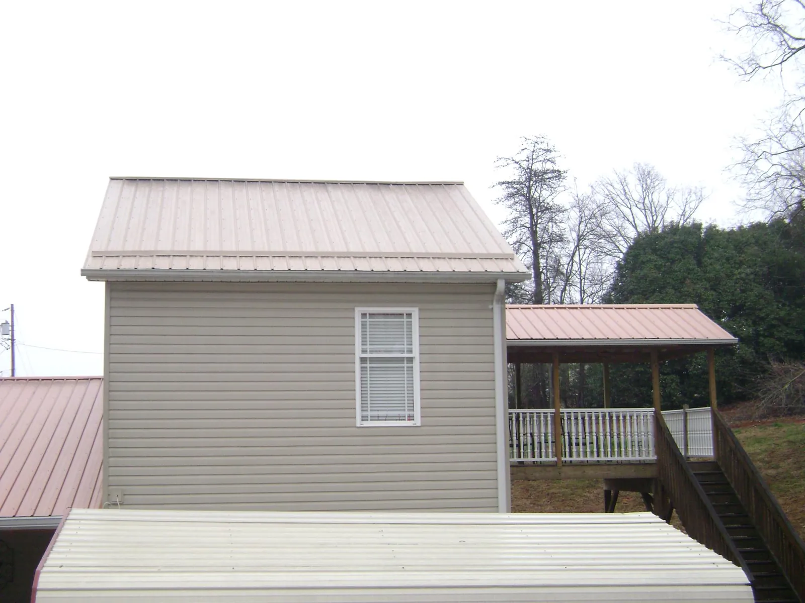 Tan metal roofs on a two story addition and attached porch, from a Roof Replacement job in Cheshire